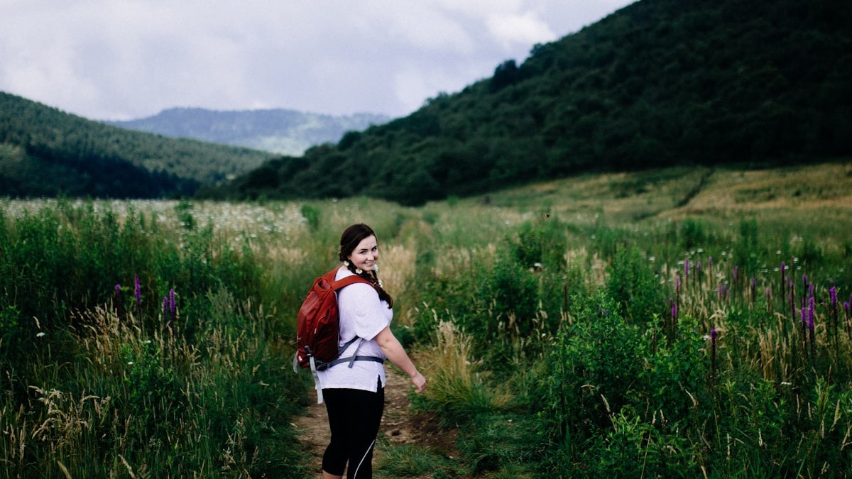 woman wearing red backpack surrounded plants